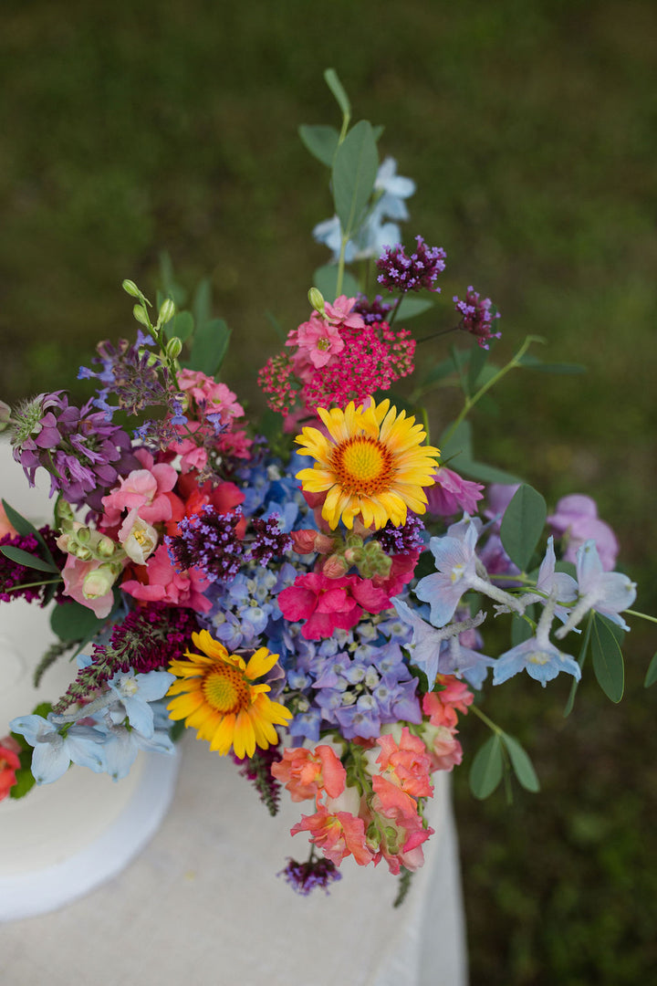 A bouquet of bright, jewel-toned flowers. Colors include yellow, pink, purple, and blue.