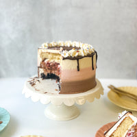A round cake frosted with three bands of different flavors: vanilla, chocolate, and strawberry. The cake has been cut into, revealing the same layers of flavor inside the cake.