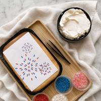 Baking tray with white icing, black border, and colorful sprinkles on a marble surface.