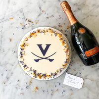 UVA graduation cake by Cake Bloom featuring a stenciled blue "V" and cavalier blue and orange edible flowers. Available for pick-up and local
