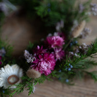 A wreath made of evergreen fronds and dried flowers.