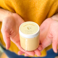 A person holding a jar of honey butter in cupped hands.