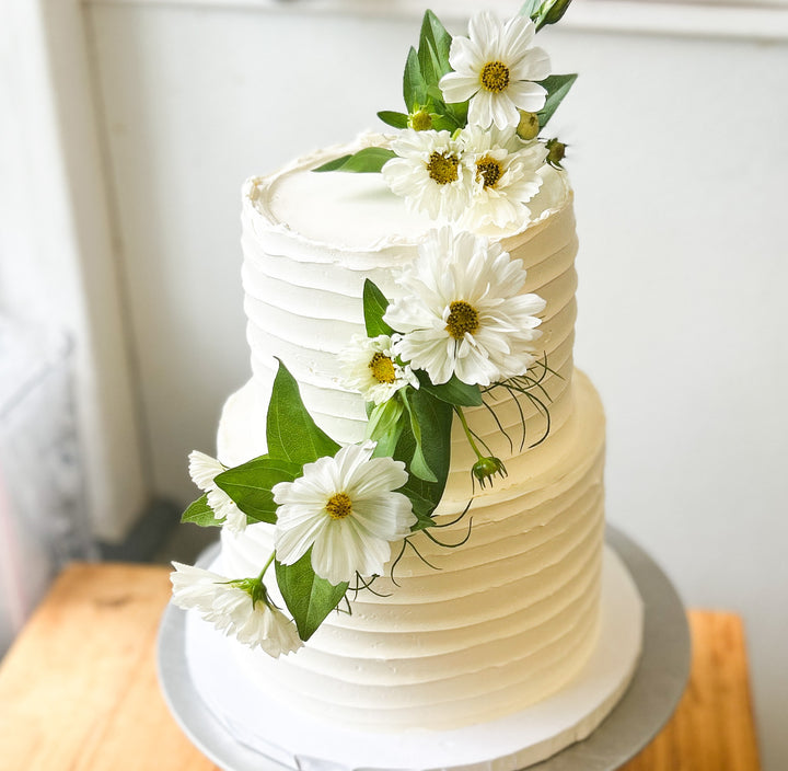 A two-tier cake decorated with a cascade of fresh white flowers.