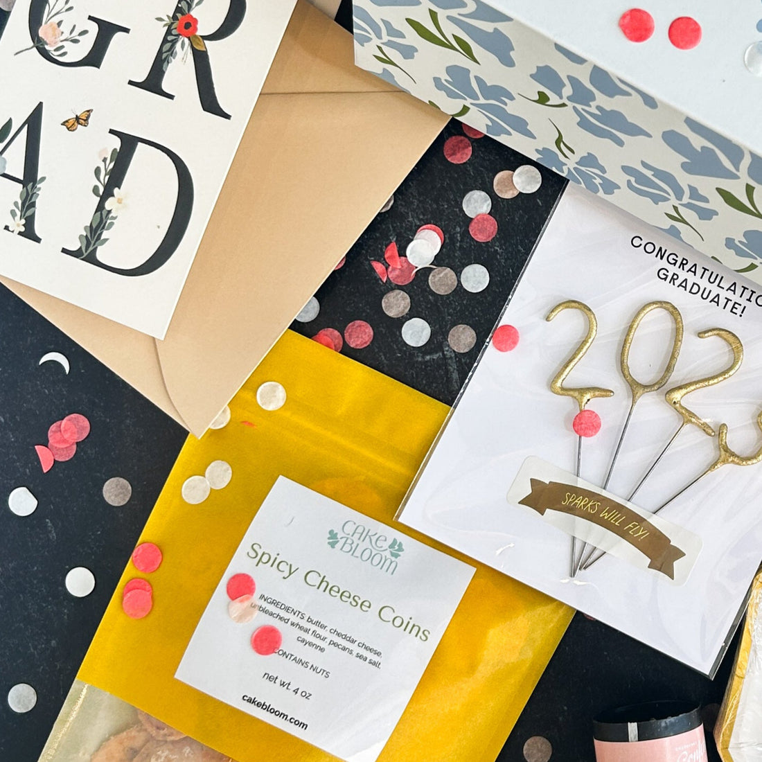 Add-ons (Deluxe Graduation Party Kit): spicy cheese coins (contains nuts), 2025 sparkler, napkins, TWO packs of plates, TWO confetti poppers, GRAD card