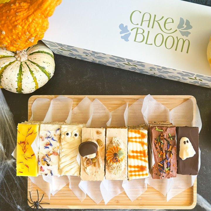 A selection of Halloween-themed cake slices with Halloween decorations, displayed in a gift box with 'CAKE BLOOM' branding.