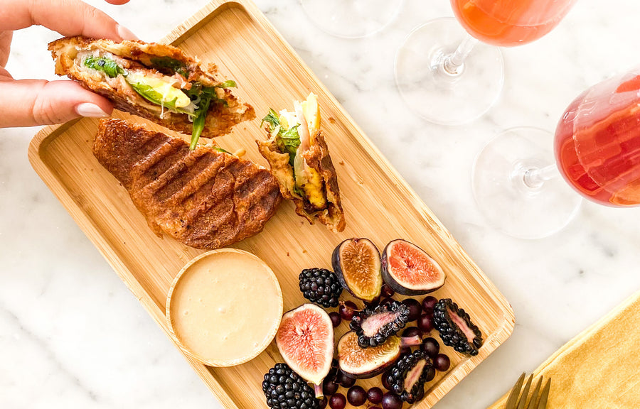 A popover panini, a side of fruit salad, and cocktails.
