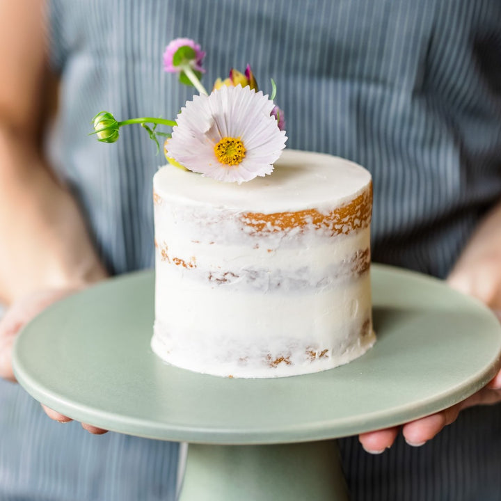 A small round cake with a large fresh flower.
