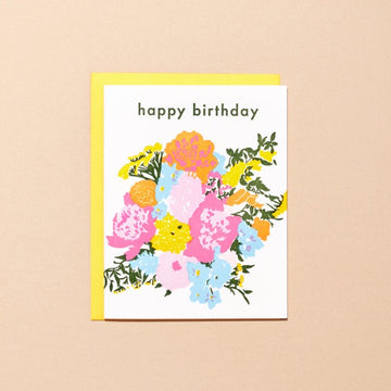 A white card with a colorful bouquet of letterpress printed flowers which reads "happy birthday". The card comes with a yellow envelope.
