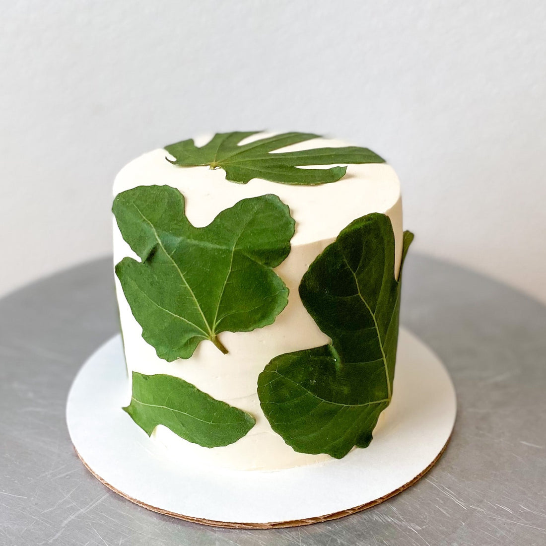 A round cake decorated with pressed fig leaves.