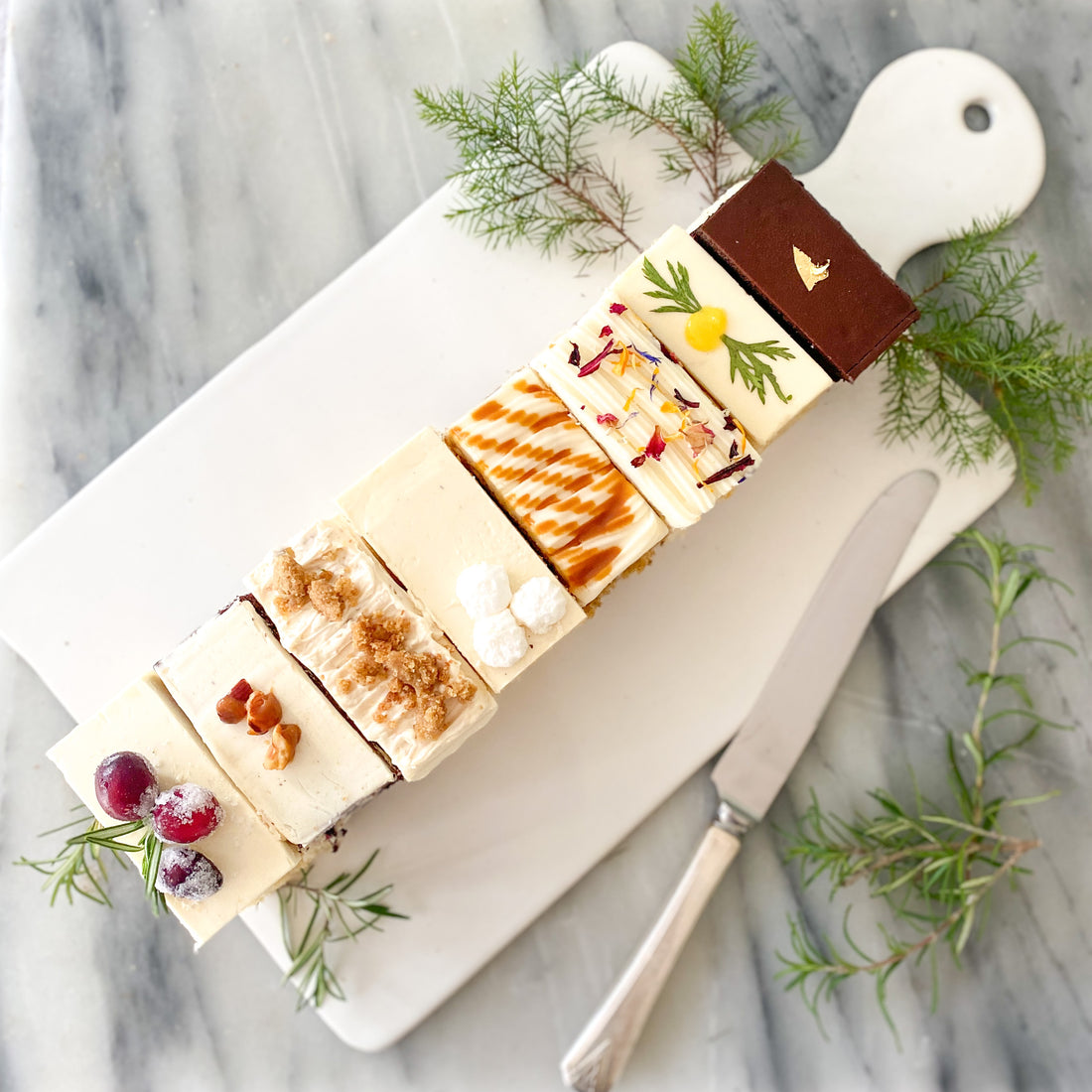 Top-down view of a platter of eight rectangular cake slices, each a different flavor.