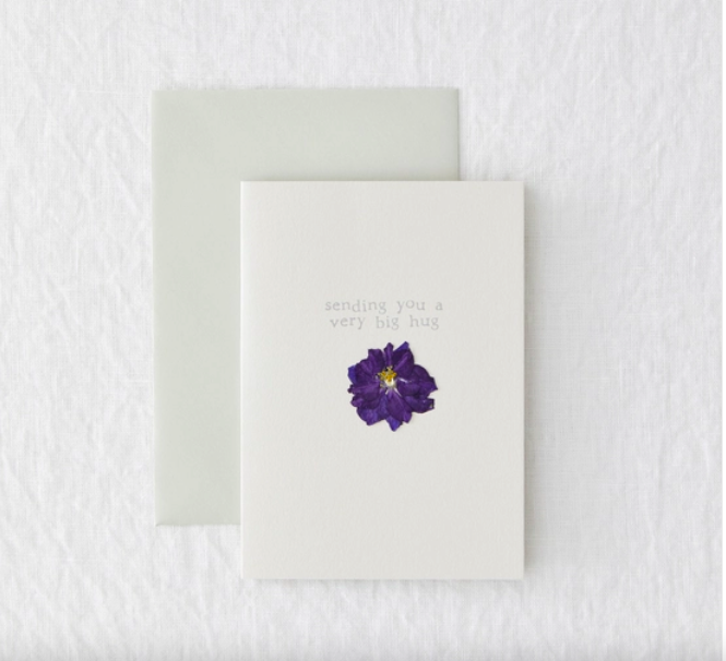 A white card with a pressed flower. "sending you a very big hug"