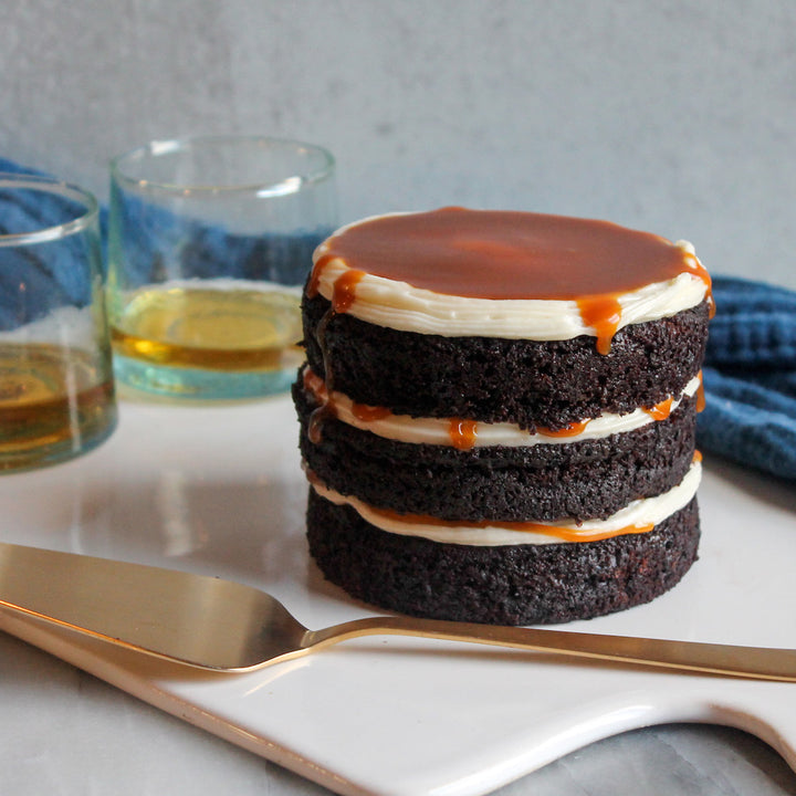A "naked" chocolate beer cake, three layers high, which is both filled and topped with cream cheese frosting and salted caramel. 