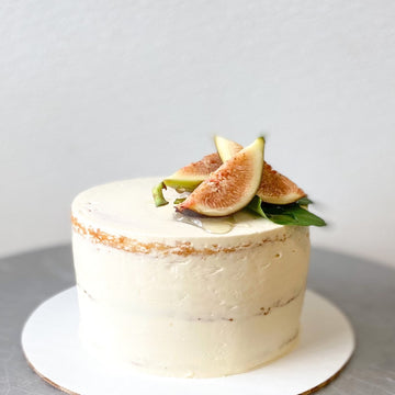 A round cake frosted with a sheer layer of buttercream and tipped with freshly-sliced, honey-drizzled figs.