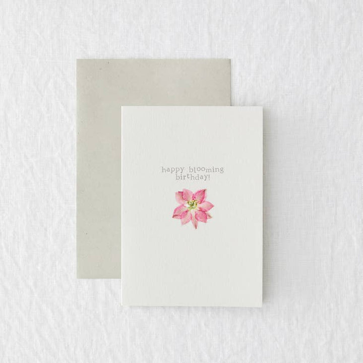 A white card with a pink pressed flower. "happy blooming birthday!"